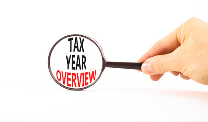 Tax year overview symbol. Concept words Tax year overview on beautiful black magnifying glass. Beautiful white background. Businessman hand. Business tax year overview concept. Copy space.