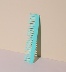 Blue plastic comb on pastel background. Beauty concept. Creative layout. Minimalism