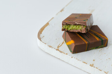 Dubai chocolate with pistachio paste and kunefe filled milk on the white cutting board . Popular food concept.