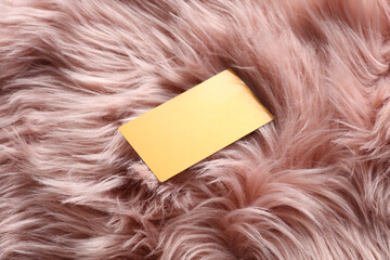 Golden business card on pink fur background.