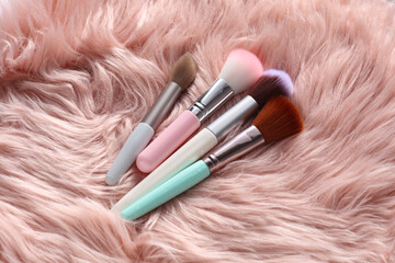 Set of makeup brushes on pink fur background