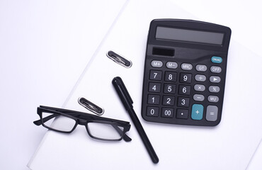 Black classic calculator with stationery on white background. Office accessories. Top view. Flat lay. Working space