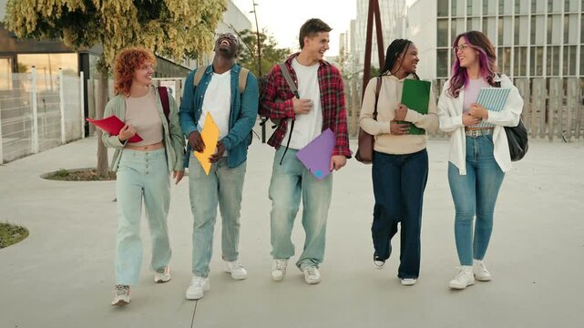 Cheerful young college student friends walking in the University campus after finishing classes and exams