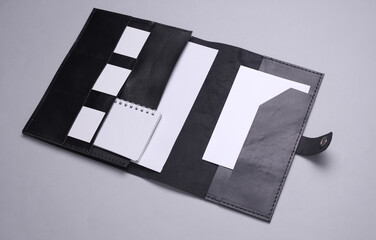 Black Leather organizer folder for paper with white business cards, notebook on gray background