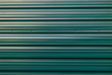 Green sheet metal wall with indentations. Concept: Building, architecture, pattern, black brick.