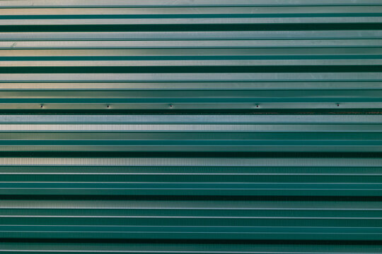 Green sheet metal wall with indentations. Concept: Building, architecture, pattern, black brick.