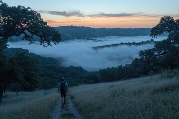 Hiker Walks Trail Through Foggy Valley Sunset