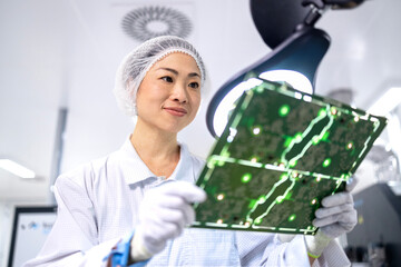 Japanese engineer or technologist inspecting quality of electronic parts in computer chip factory.