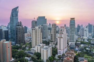 Fototapeta premium Urban skyline of Bangkok during sunset with buildings reflecting golden light
