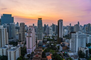 Obraz premium Skyline view of Bangkok at sunset with towering buildings reflecting warm colors and a tranquil atmosphere