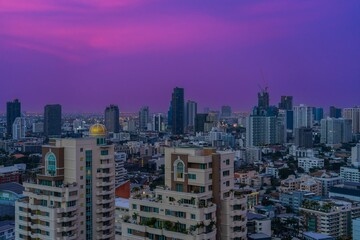 Obraz premium Vibrant sunset colors illuminate the skyline of Bangkok with towering buildings and a bustling urban landscape