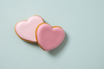 Fototapeta premium Heart shaped cookie with pink glaze on pastel blue background. Valentines day greeting card. View from above. Copy space. Love concept.
