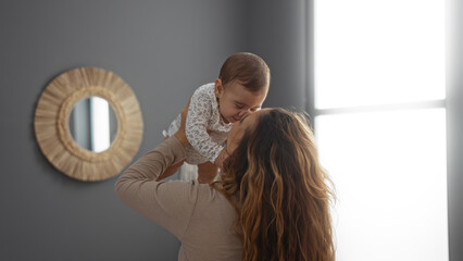 Mother lifting smiling baby in cozy living room showing love and affection in peaceful home setting
