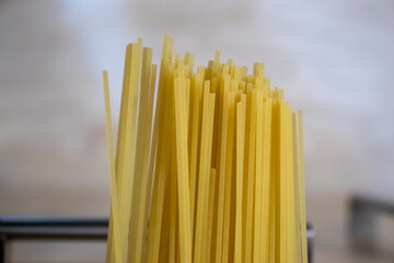 Close-up of uncooked spaghetti pasta in a bundle, featuring vibrant yellow strands. Ideal for food...