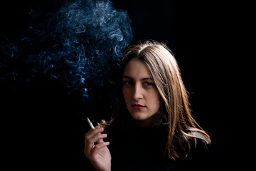 Obraz premium Young woman smoking cigarette on black background