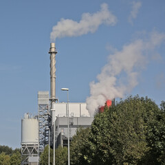 Industrial building with smoking chimneys and silo on a sunny day in the harbour of Ghent,...