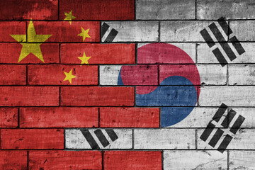colourful painted big flag of china and flag of south korea on a massive old brick wall background....