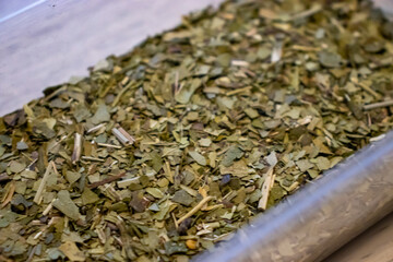 Close-up view of dried herbs arranged in a container, showcasing their textures and colors. Ideal for culinary or health-related themes.