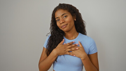 Young hispanic woman with hands on chest smiling against white background