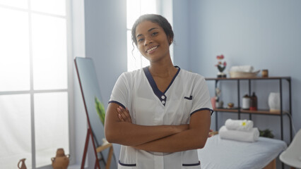 Female spa worker standing confidently in a wellness center room with arms crossed in an indoor setting of a beauty salon