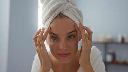 Woman relaxing indoors at a wellness spa with a towel wrapped around her head, highlighting her beautiful and attractive features in a serene salon environment.