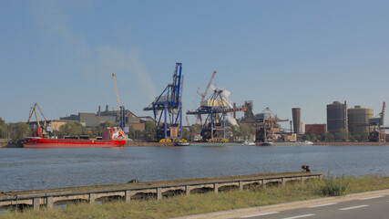  Canal with cargo ship and cranes, silo`s and other industrial buildings on the embankment in...