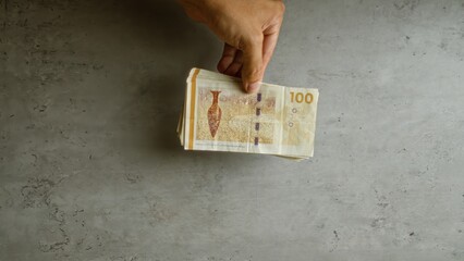 Hand holding a stack of danish krone bills against a concrete background, emphasizing currency and...