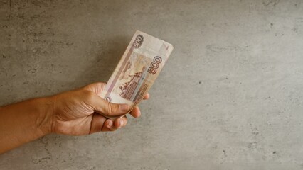 Male hand holding russian rubles against a concrete background giving a focus on the 500...