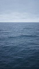 Blue ocean under cloudy sky depicting calm serene natural seascape with horizon in the distance suggesting tranquility and vast expanse outdoor scenery.