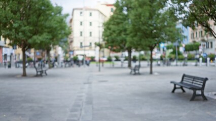 Blurry scene of la spezia street with benches, trees, and buildings in europe providing a serene urban setting.