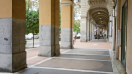 Fototapeta premium Defocused view of a street in la spezia, italy, showcasing blurred architecture and bokeh effect, capturing the essence of a bustling european town under elegant archways.