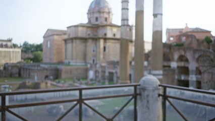 Fototapeta premium Blurred view of the ancient roman forum in rome with defocused ruins, showcasing historical architecture and columns under a clear sky.