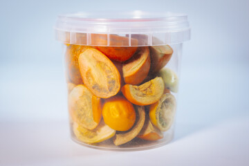 A clear plastic container filled with freeze-dried tomatoes of various colors and cuts. Vibrant orange and yellow tones dominate. Ideal for long-term storage and culinary uses.
