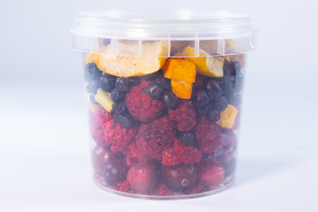 A transparent jar filled with a colorful assortment of freeze-dried fruits and vegetables, including blueberries, cranberries, raspberries, apple slices, pumpkin cubes, and more.