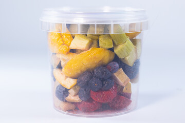 A transparent jar filled with a colorful assortment of freeze-dried fruits and vegetables, including blueberries, cranberries, raspberries, apple slices, pumpkin cubes, and more.