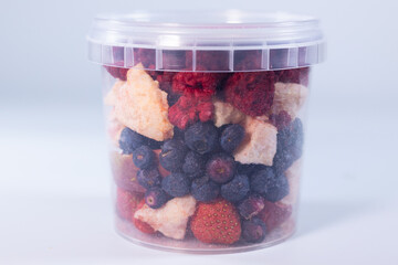 A transparent jar filled with a colorful assortment of freeze-dried fruits and vegetables, including blueberries, cranberries, raspberries, apple slices, pumpkin cubes, and more.
