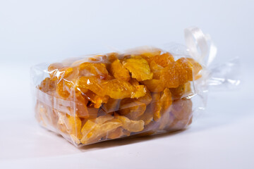 A clear container filled with freeze-dried quince pieces, highlighting their golden-yellow hue and...