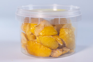 A clear container filled with freeze-dried quince pieces, highlighting their golden-yellow hue and...