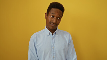 Obraz premium Young african american man posing against an isolated yellow background exuding a confident and attractive presence.