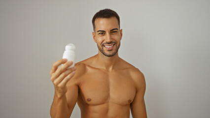 Fototapeta premium Young hispanic man with beard holding deodorant over isolated white background