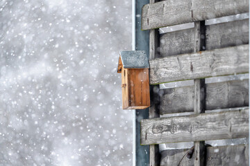 A birdhouse is sitting on a wooden fence in the snow