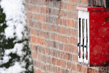 A red vending machine with three compartments is covered in snow
