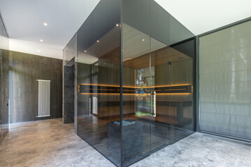 Stylish design of a sauna with glass walls in the interior of a country house.