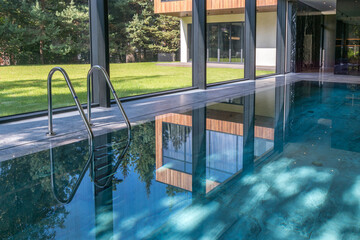 Beautiful summer landscape outside the window of a private swimming pool. The glare of the sun on...
