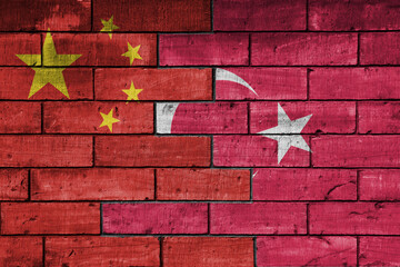 colourful painted big flag of china and flag of turkey on a massive old brick wall background....