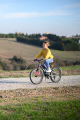 Fototapeta premium a girl race her bicycles through the countryside at sunset, laughing and chasing each other. The golden light and peaceful surroundings create a joyful, carefree moment of childhood advent