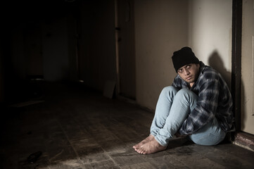 A drug addict is paranoid after taking drugs, sitting in the hallway of an abandoned building.