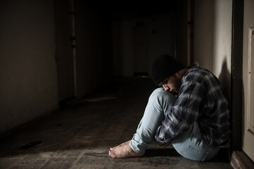 A drug addict is paranoid after taking drugs, sitting in the hallway of an abandoned building.