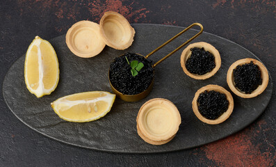 Black sturgeon caviar and empty round tartlets on table, top view