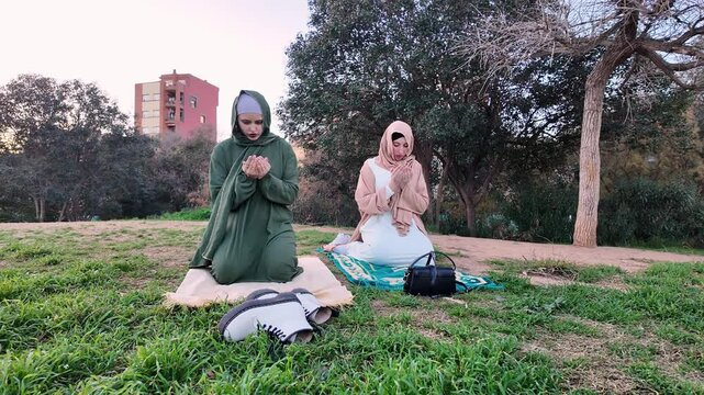 Muslim women praying together in park during ramadan